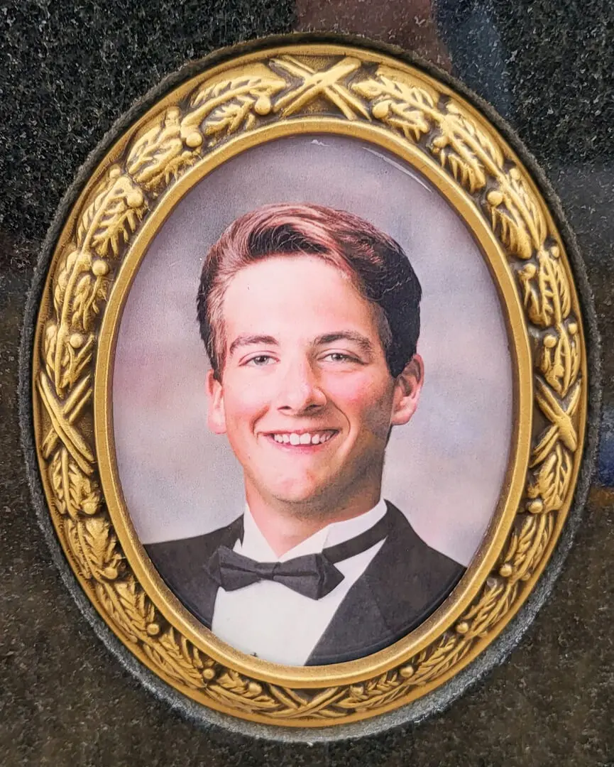 A picture of a young man wearing a bowtie engraved on a memorial slab
