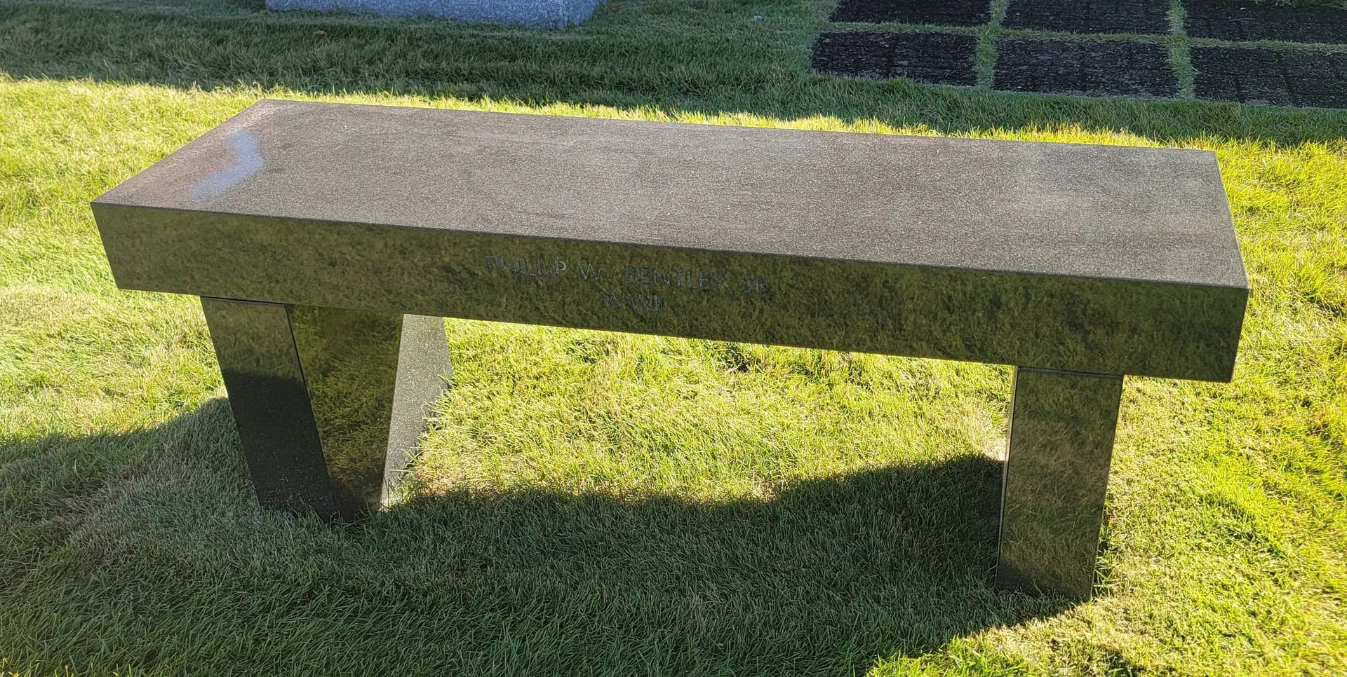 A picture of a brown color marble bench at a funeral