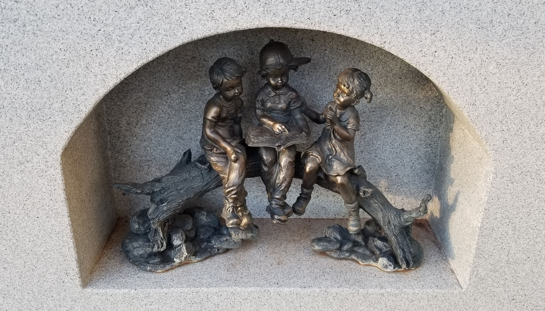 A beautiful statue of children sitting on a piece of log