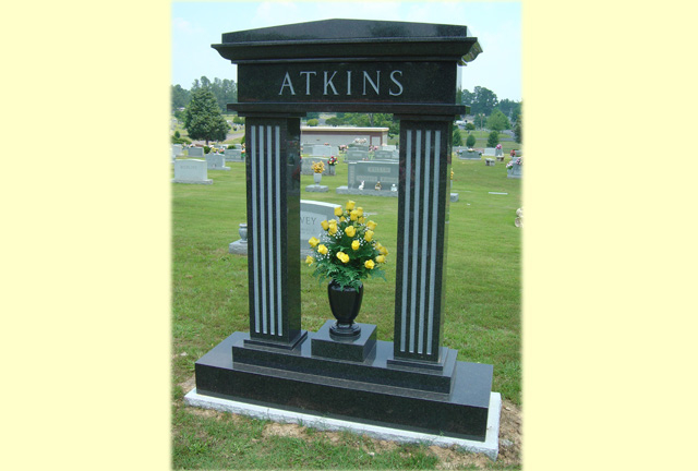 A memorial slab with the name Atkins with beautiful yellow flowers