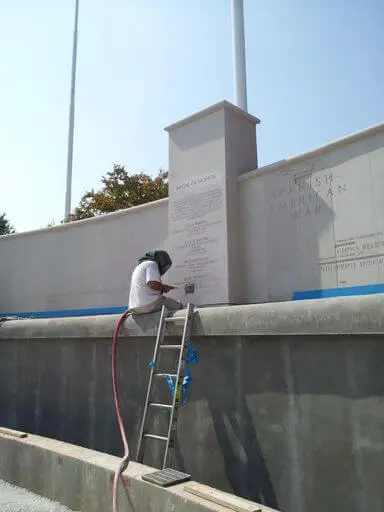 A Man Sitting Infront of a Memorial Wall Spraying