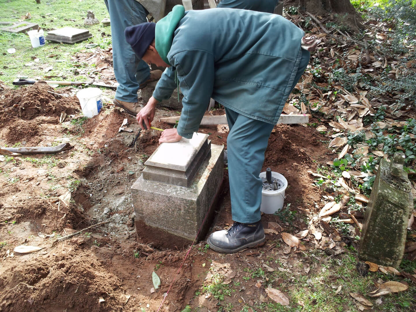 A Man Fixing a Stone Tombstone in Land