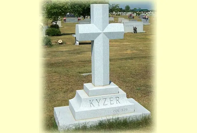 A cross shaped memorial slab with the name Kyzer