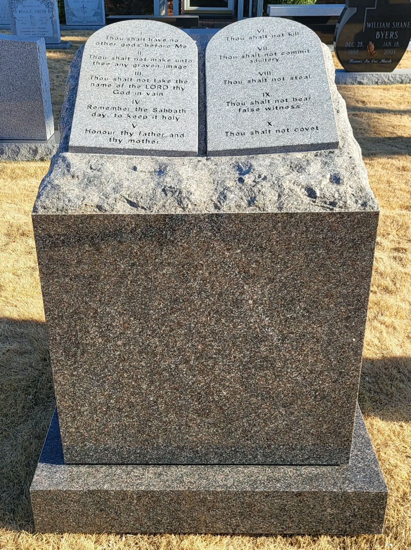 A memorial slab with the quote of the bible in the shape of a book
