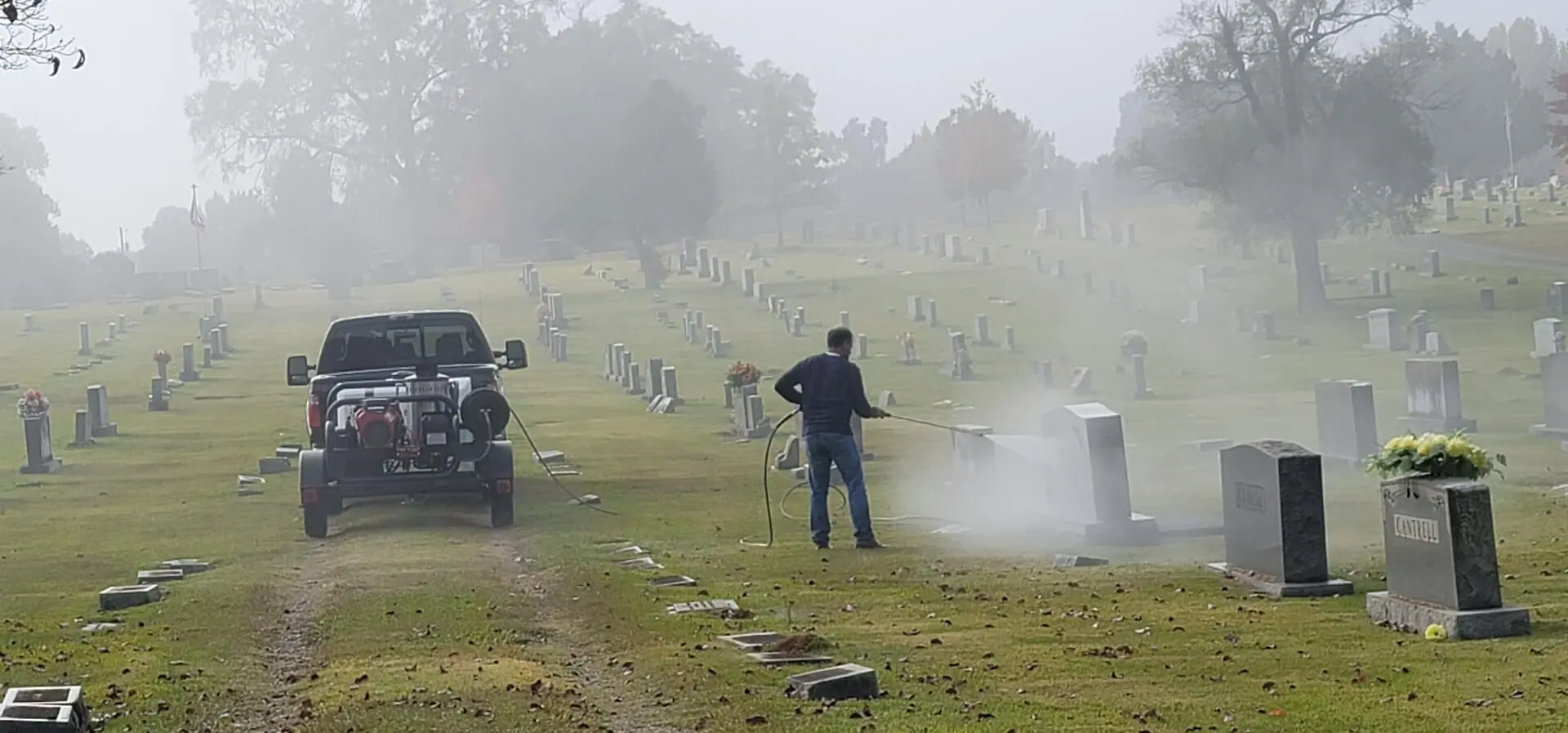 A Man Cleaning Tombstones in a Line