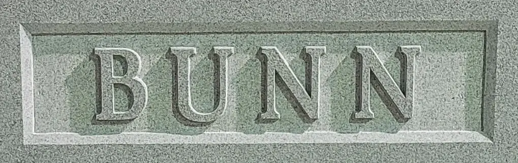 An illustration and logo engraved on a memorial slab that says Bunn