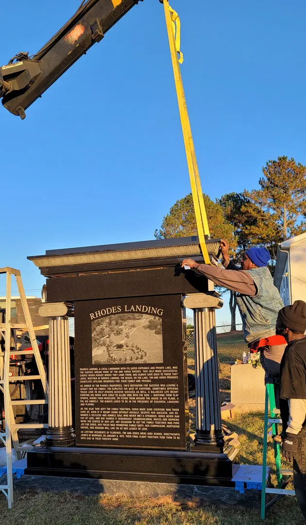 A Crane Lowering a Tombstone With a Picture Engraving
